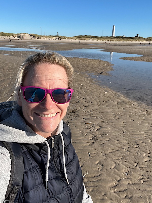 Frau am Strand und im Hintergrund ein Leuchtturm
