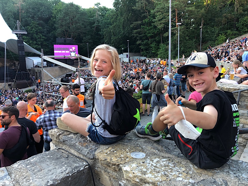 Zwei Kinder sitzen in der Waldbühne Berlin und schauen in die Kamera